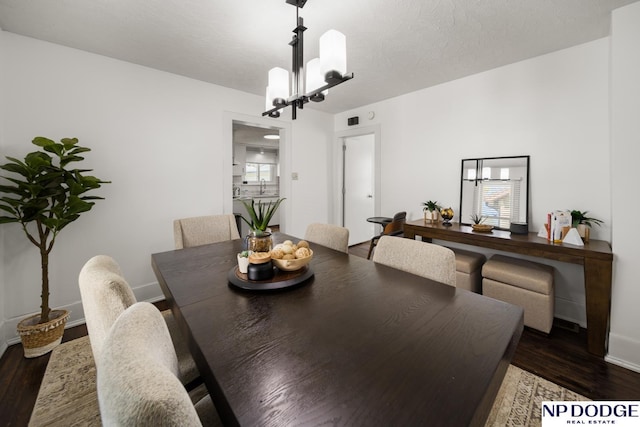 dining space with baseboards, a chandelier, and wood finished floors