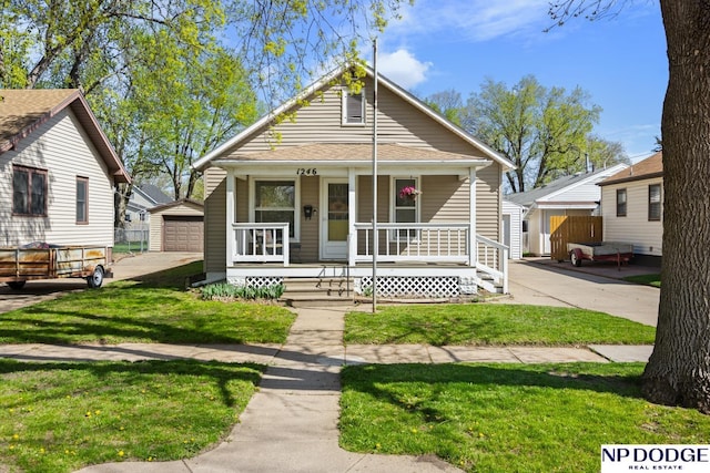 view of front of property featuring a porch, an outbuilding, a detached garage, and a front yard