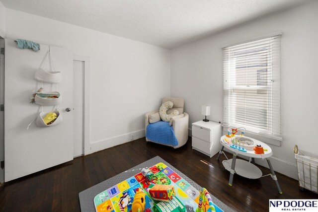 recreation room featuring baseboards, wood finished floors, and radiator