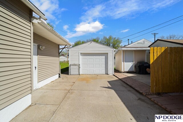 detached garage featuring driveway and fence