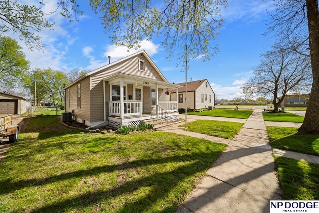 view of front of home with covered porch, a front yard, and central AC unit