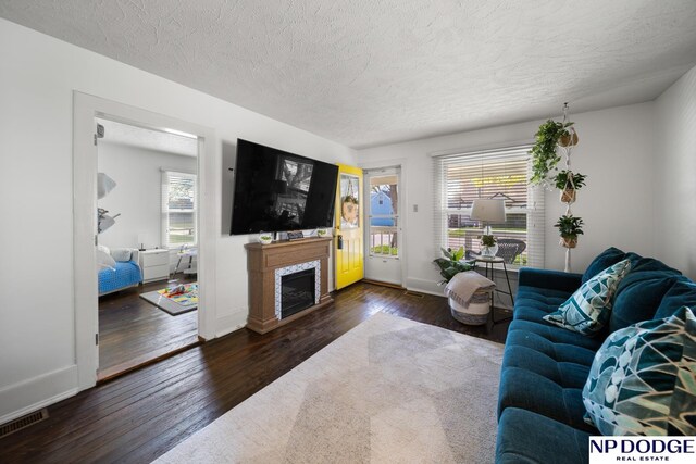living room featuring wood-type flooring, a textured ceiling, visible vents, and plenty of natural light