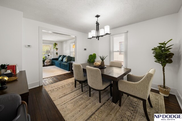 dining space featuring a wealth of natural light, a notable chandelier, dark wood-style flooring, and baseboards