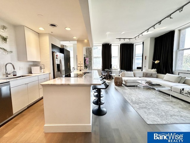 kitchen featuring track lighting, modern cabinets, a sink, appliances with stainless steel finishes, and open floor plan