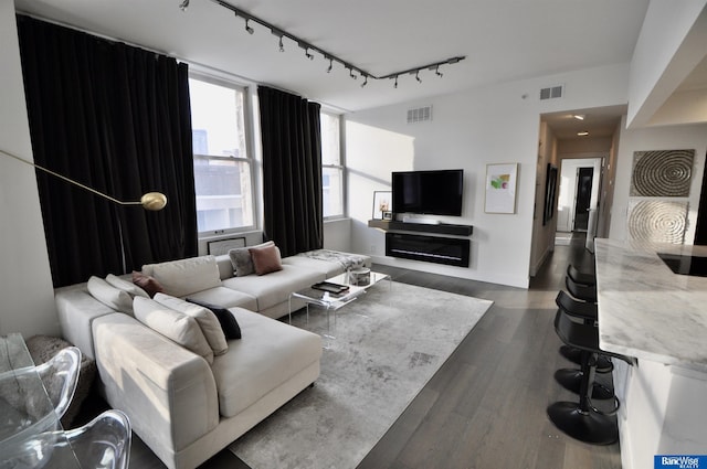 living area featuring dark wood-style floors, visible vents, and rail lighting
