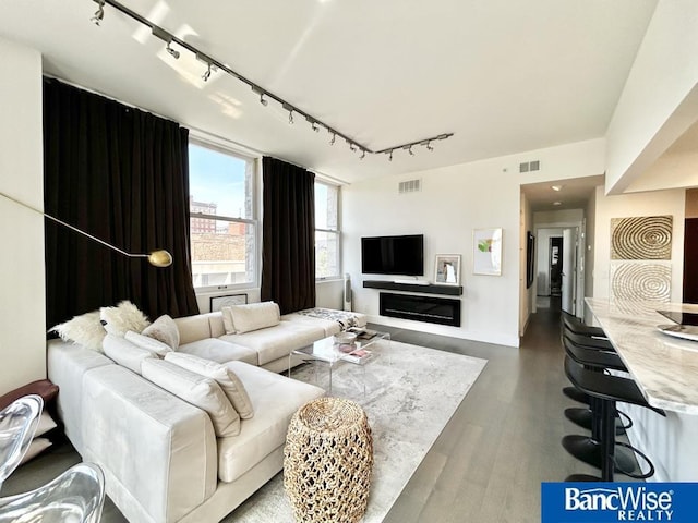 living area with wood finished floors, rail lighting, and visible vents