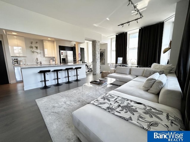 living room with rail lighting, ornate columns, and dark wood finished floors