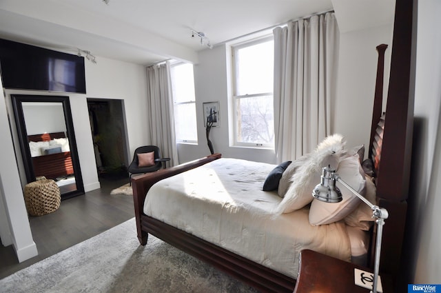 bedroom featuring track lighting and wood finished floors
