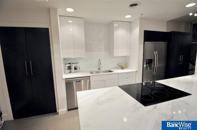 kitchen with a sink, modern cabinets, white cabinets, appliances with stainless steel finishes, and visible vents
