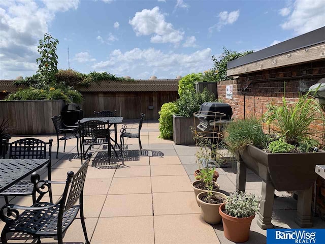 view of patio featuring a fenced backyard, outdoor dining area, and a grill