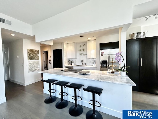 kitchen with stainless steel fridge with ice dispenser, dark wood-style flooring, a breakfast bar, and visible vents