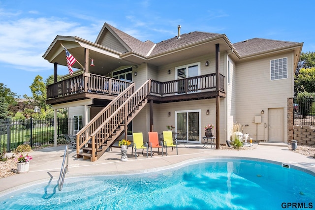 rear view of house with fence, a patio, a deck, and a fenced in pool