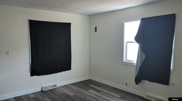 empty room with dark wood finished floors, baseboards, and visible vents