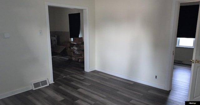 spare room with baseboards, visible vents, and dark wood finished floors