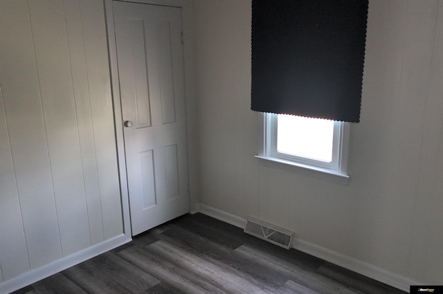 unfurnished bedroom featuring baseboards, dark wood-style flooring, and visible vents