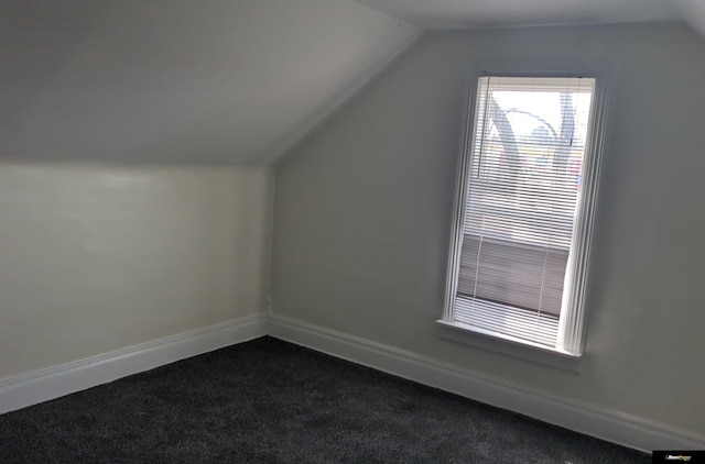 bonus room featuring lofted ceiling, dark colored carpet, and baseboards