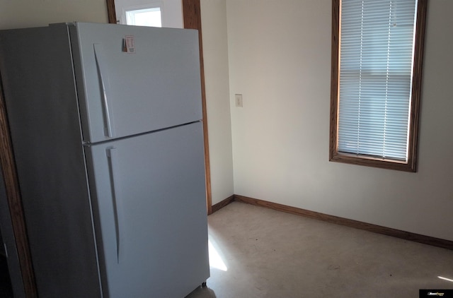 kitchen with concrete floors, freestanding refrigerator, and baseboards