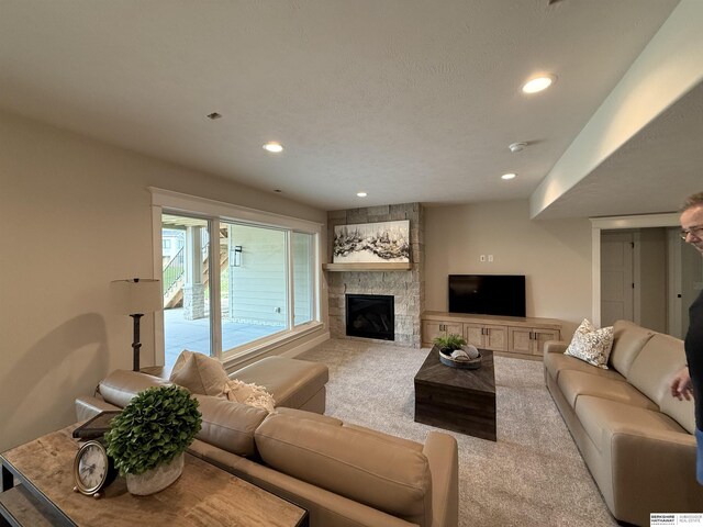 living room with recessed lighting, a stone fireplace, and carpet floors