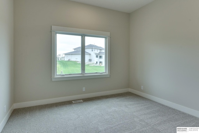 carpeted spare room with visible vents and baseboards