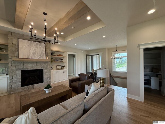 living area with an inviting chandelier, a fireplace, built in features, baseboards, and wood finished floors