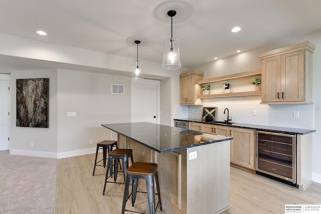 kitchen featuring open shelves, a sink, a kitchen island, light brown cabinetry, and wine cooler