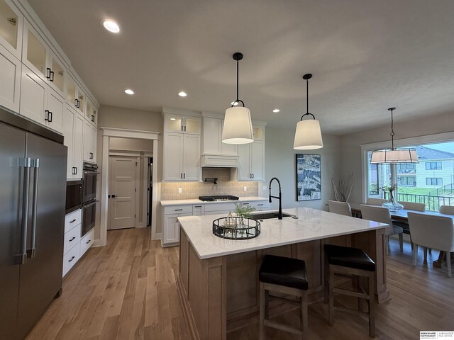 kitchen featuring a sink, light wood-type flooring, white cabinetry, backsplash, and high quality fridge