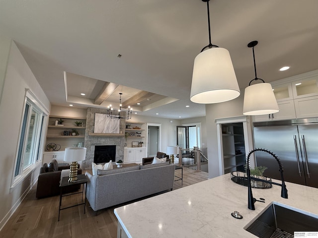 kitchen with light stone counters, built in features, wood finished floors, and a sink