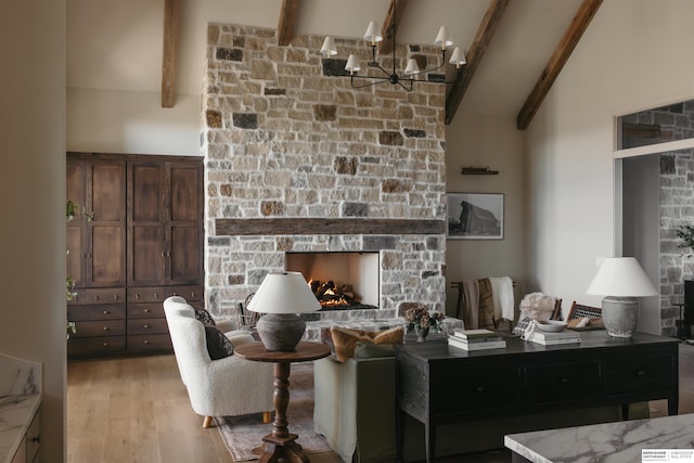 living room with high vaulted ceiling, a stone fireplace, an inviting chandelier, light wood finished floors, and beam ceiling
