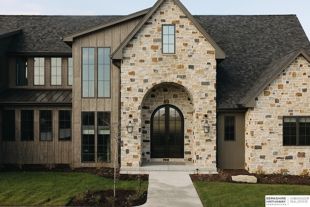 view of front of property featuring stone siding, a standing seam roof, a shingled roof, and french doors
