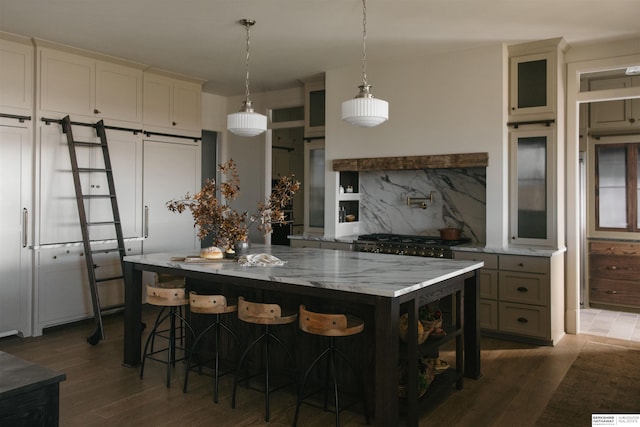kitchen featuring a barn door, light stone countertops, a center island, tasteful backsplash, and dark wood-style flooring