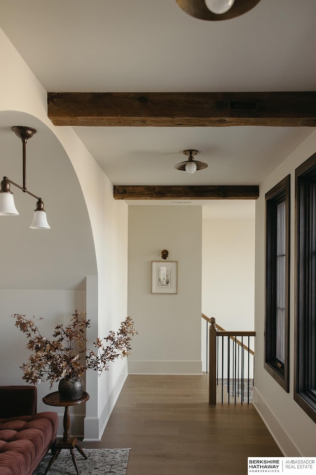 hall with dark wood finished floors, baseboards, and beam ceiling