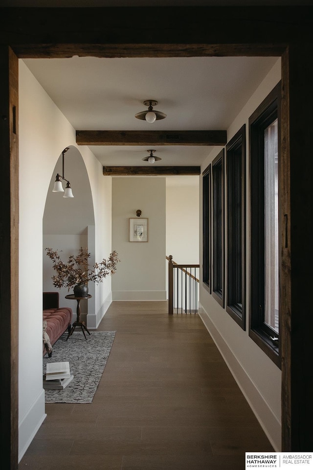 corridor with baseboards, beam ceiling, and dark wood-style flooring