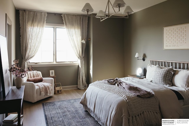 bedroom with baseboards, a notable chandelier, and wood finished floors