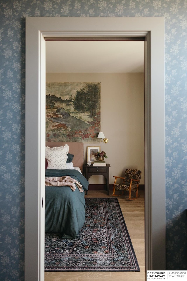 bedroom featuring wood finished floors and wallpapered walls