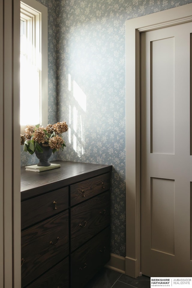 interior space featuring wallpapered walls, baseboards, tile patterned floors, and vanity