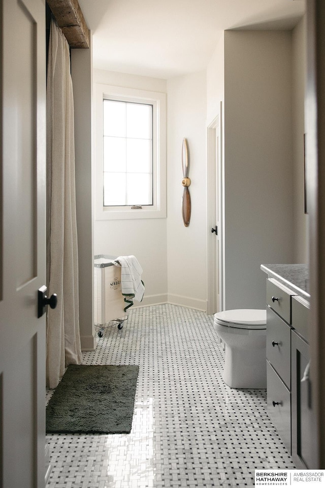 bathroom with baseboards, vanity, and toilet