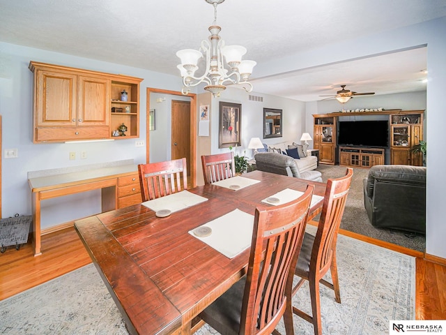 dining room with light wood-type flooring, a chandelier, and ceiling fan