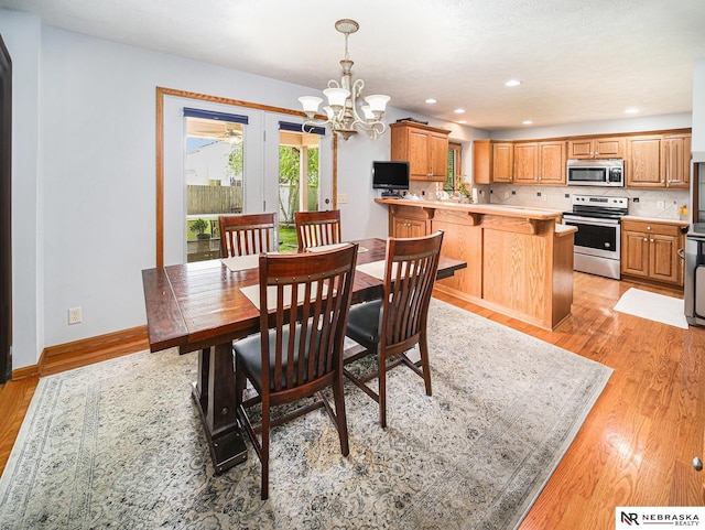 dining area featuring light wood finished floors, a chandelier, recessed lighting, and baseboards