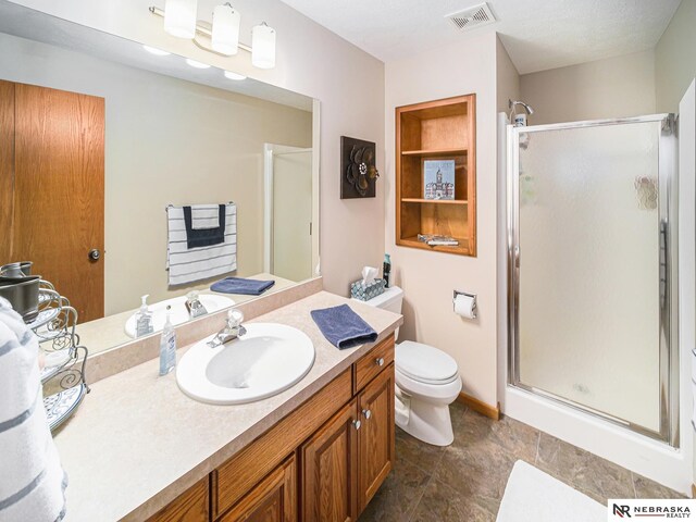bathroom featuring a stall shower, toilet, and vanity