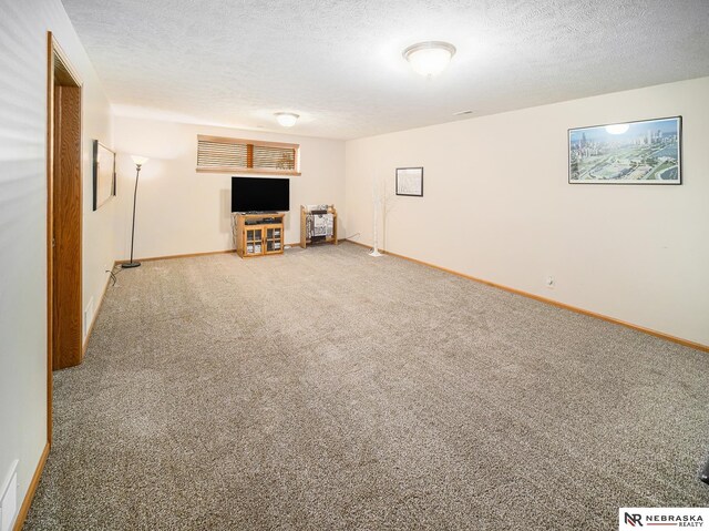finished below grade area featuring carpet floors, baseboards, and a textured ceiling