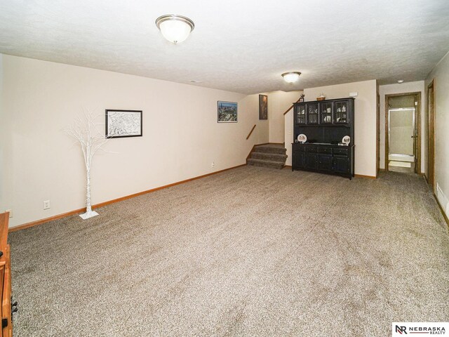 unfurnished living room featuring stairs, carpet, and baseboards