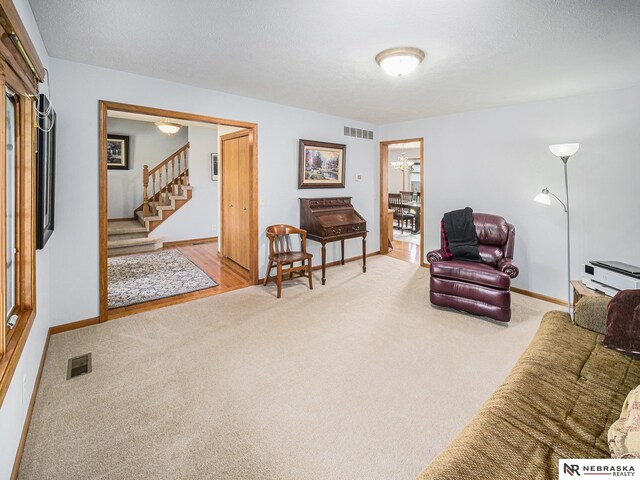 carpeted living room with stairs, baseboards, and a chandelier