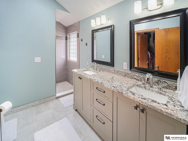 full bath featuring walk in shower, lofted ceiling, double vanity, baseboards, and tile patterned floors
