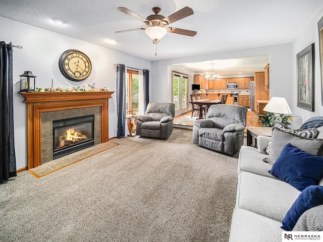 carpeted living room featuring a chandelier, ceiling fan, and a fireplace