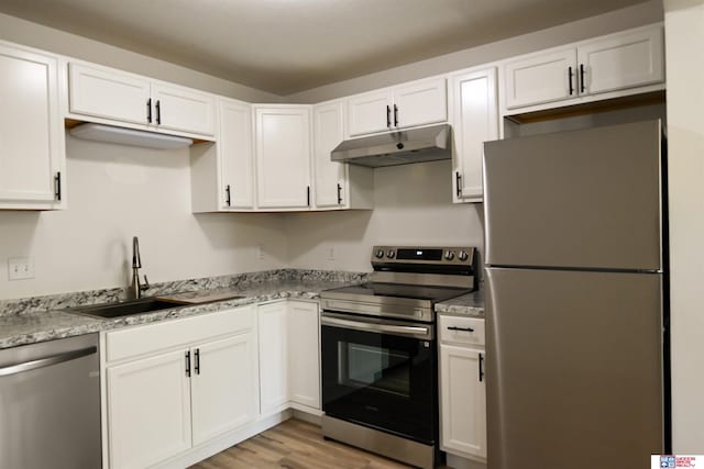 4915 Walker Ave, Lincoln, NE 68504 - kitchen with appliances with stainless steel finishes, under cabinet range hood, a sink, white cabinetry, and light wood finished floors