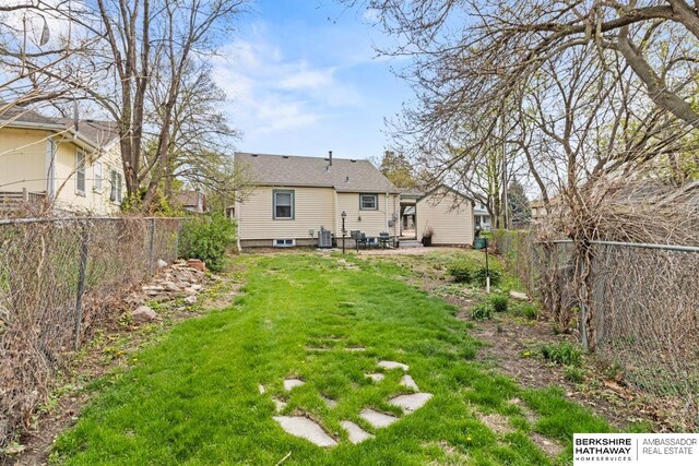 view of yard with a fenced backyard, central air condition unit, and a patio area