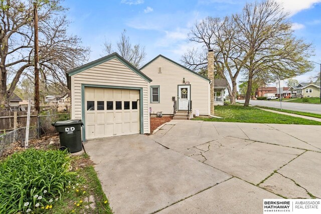 view of front facade featuring a chimney, concrete driveway, fence, entry steps, and an attached garage