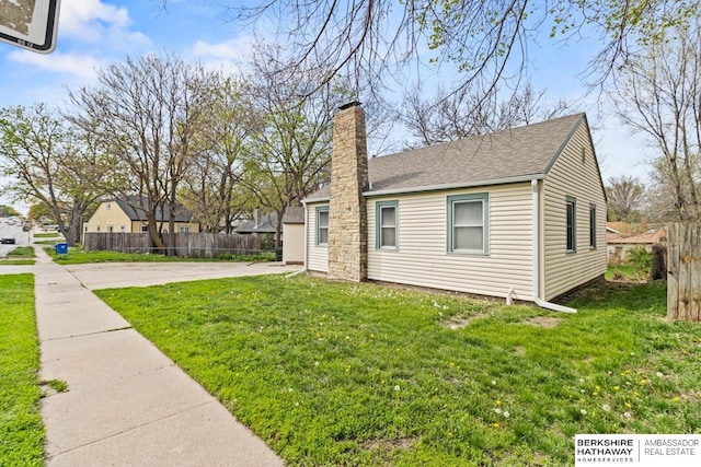 view of property exterior with roof with shingles, a chimney, fence, and a lawn