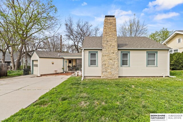 view of front of house with a chimney, covered porch, a front yard, and roof with shingles