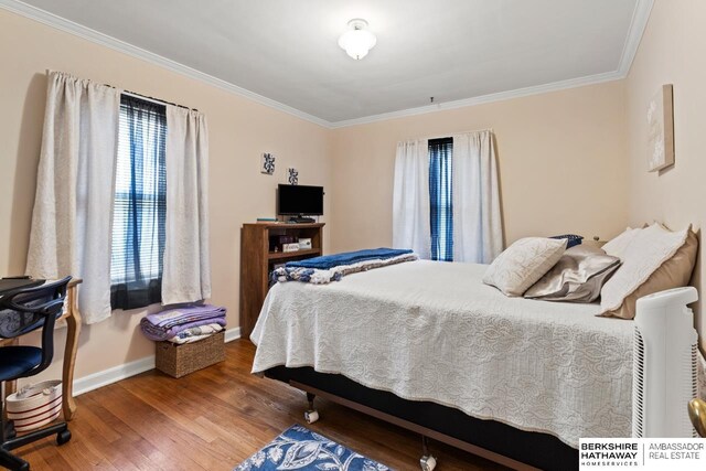 bedroom with wood finished floors, crown molding, and baseboards